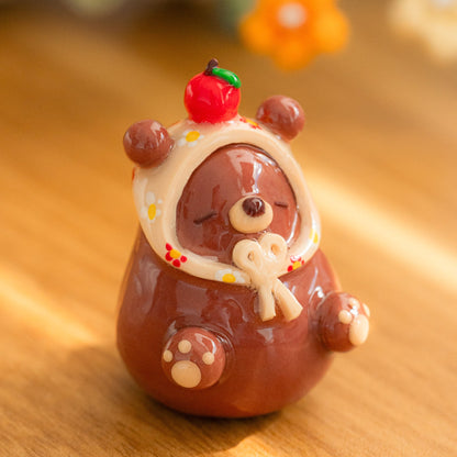 A cozy bear figurine with a babushka scarf made from polymer clay.